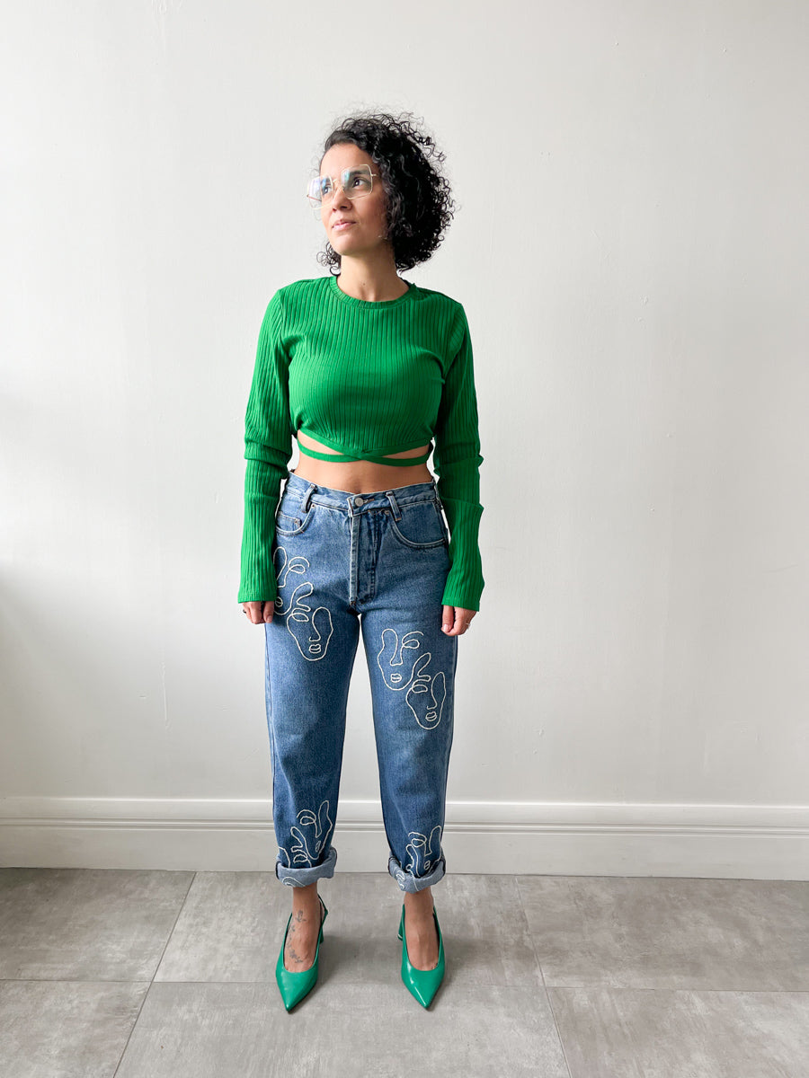 Fanfare Label sustainable women’s clothing brand UK. Our upcycled jeans are high-waisted, blue denim and made from recycled denim. We decorate every jean with a white embroidered thread in a face design.