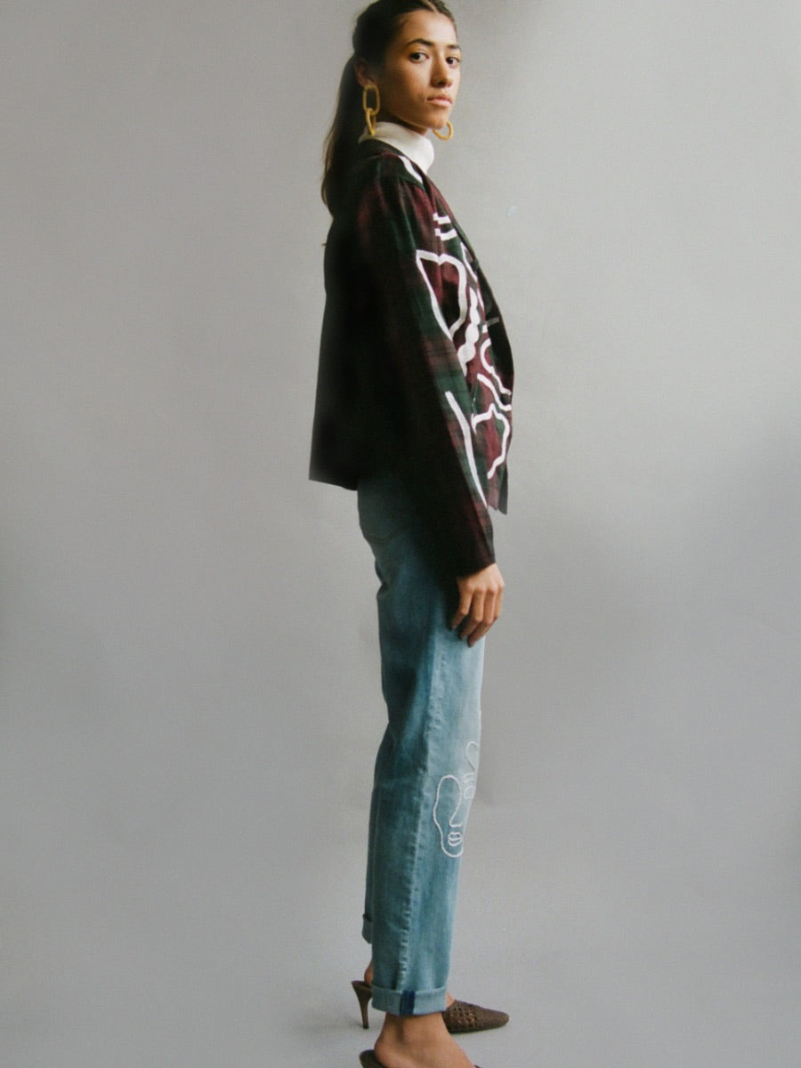 Fanfare Label sustainable women’s clothing brand UK. Our upcycled jeans are high-waisted, blue denim and made from recycled denim. We decorate every jean with a white embroidered thread in a face design.