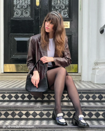 Ambre porte les mocassins à talons PABLO avec une jupe et un blazer en cuir marron