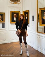 Louise porte les bottes CRISTOBAL à talon en cuir argent avec un short et une blouse noire